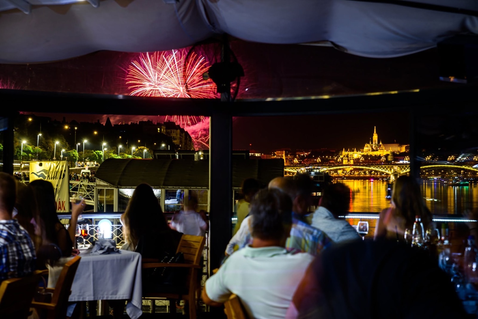 Guests on board watching the fireworks over the Danube, Margaret Bridge lit behind